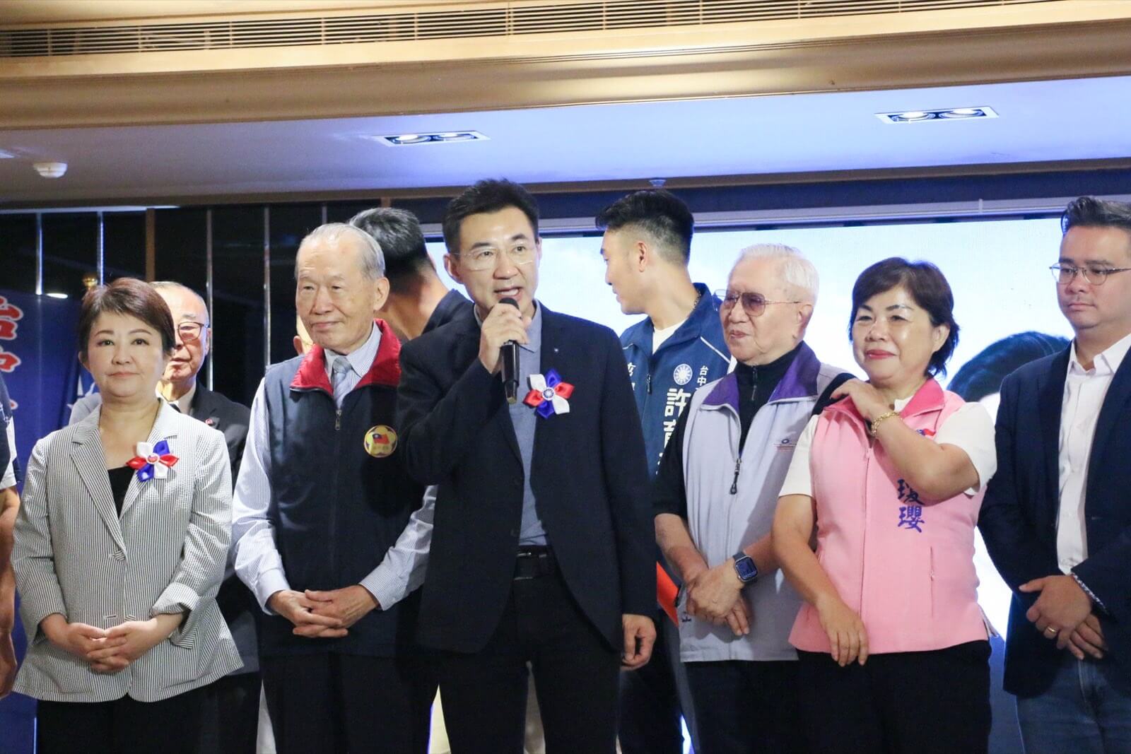 江啟臣在臺中市各界慶祝八二三砲戰勝利六十八週年大會上持麥克風致詞，盧秀燕與國軍前輩在旁聆聽