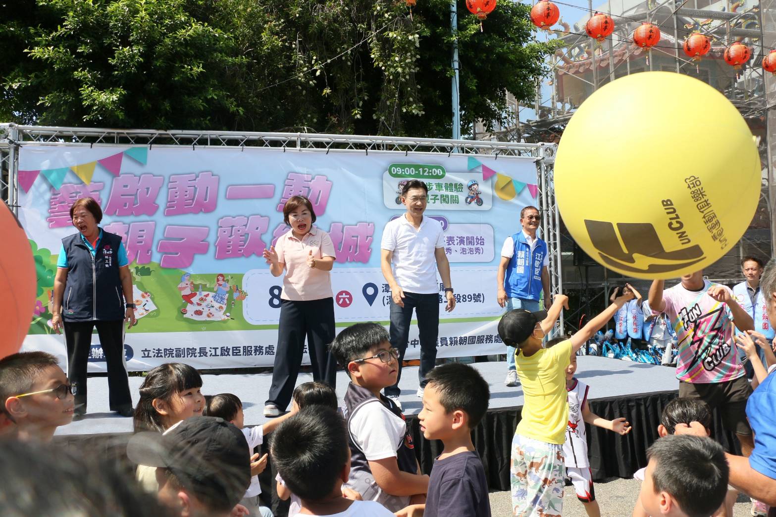親子歡樂城舞台前的孩子們伸手搶接大黃氣球，江啟臣與楊瓊瓔在舞台上帶動氣氛