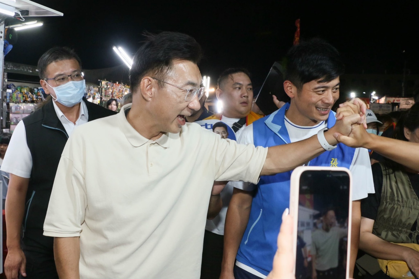 江啟臣在夜市與支持者握手，身旁民眾舉起手機記錄