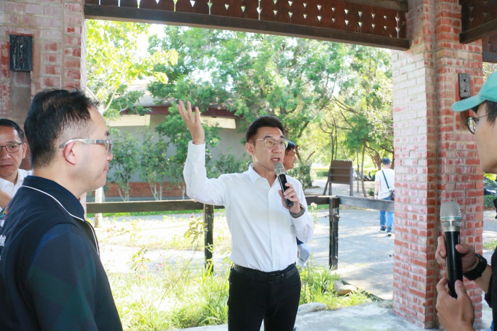 江啟臣在園區紅磚迴廊下持麥克風說明園區改造構想