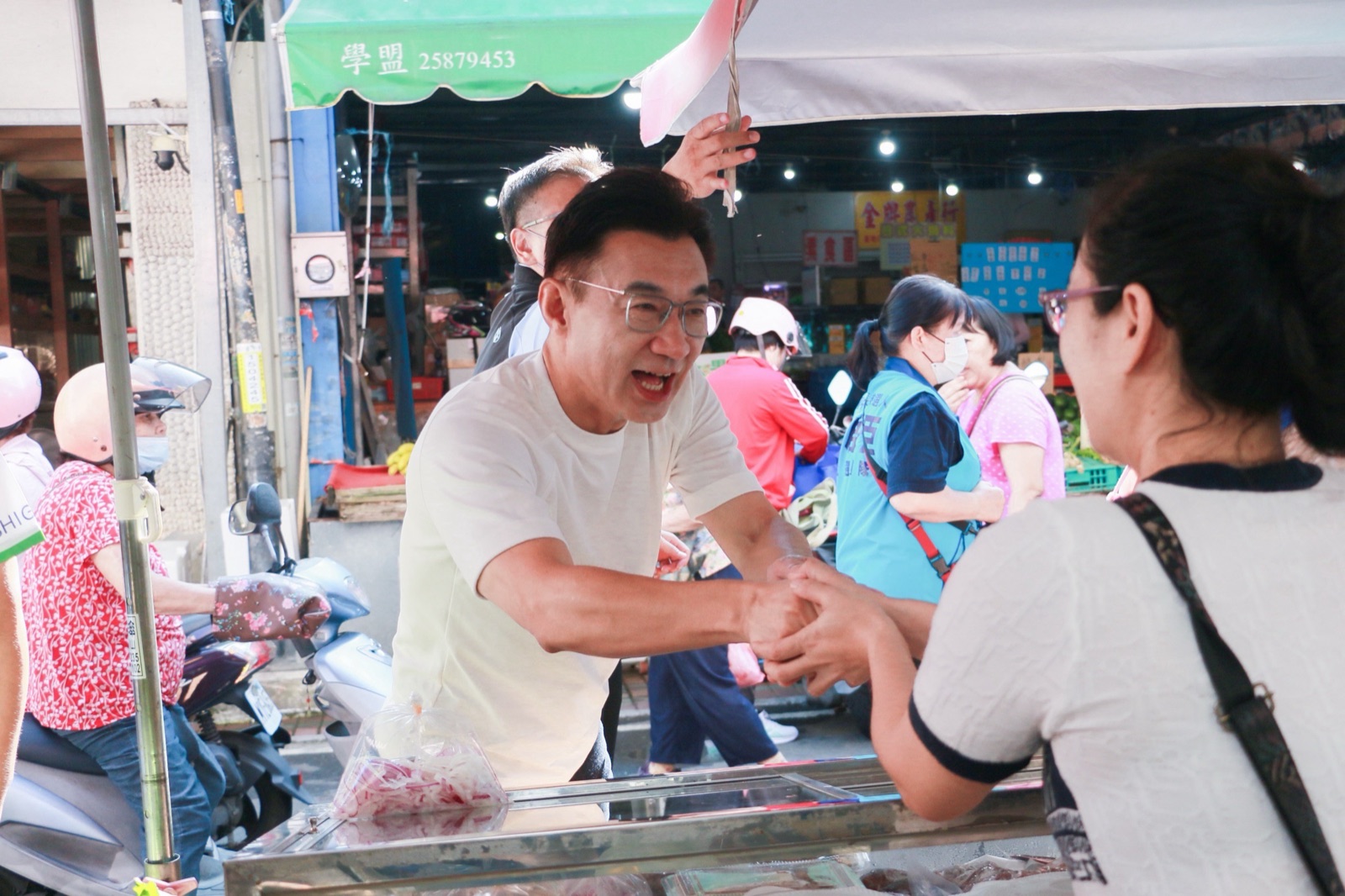 江啟臣在市場攤位前與攤商握手致意