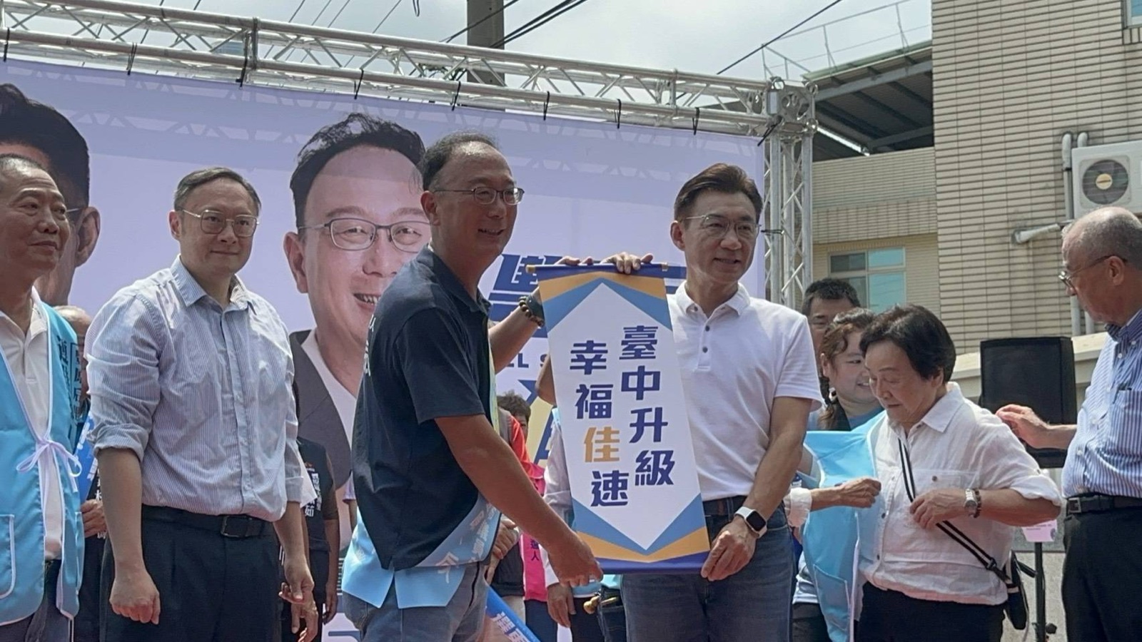 支持者致贈「臺中升級　幸福佳速」錦旗，江啟臣在台上合影