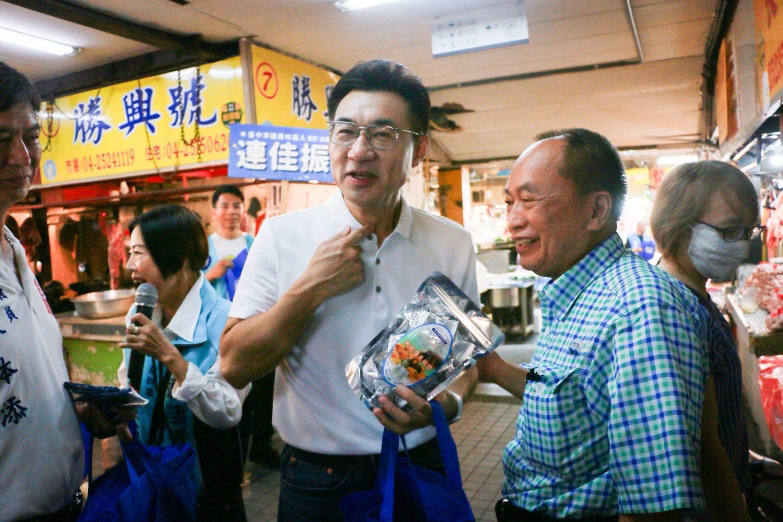 市場採買的民眾送上枇杷喉糖，江啟臣指著喉嚨笑著道謝