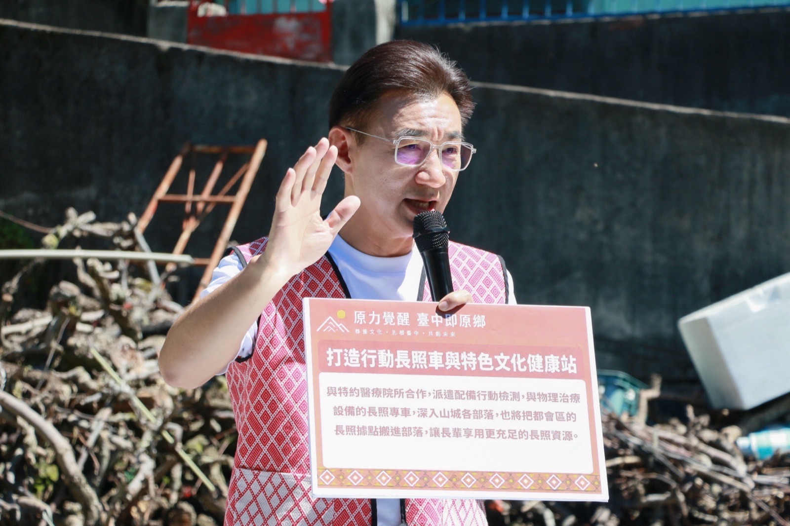 江啟臣手持「打造行動長照車與特色文化健康站」政策看板，說明原住民族政策