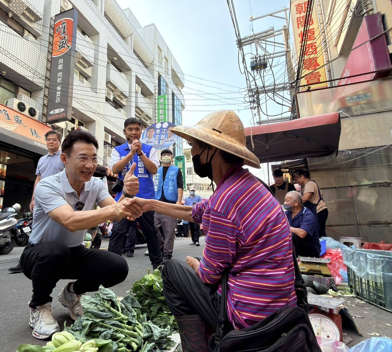 江啟臣蹲下與路邊菜攤的農民握手，市議員李文傑在旁比讚