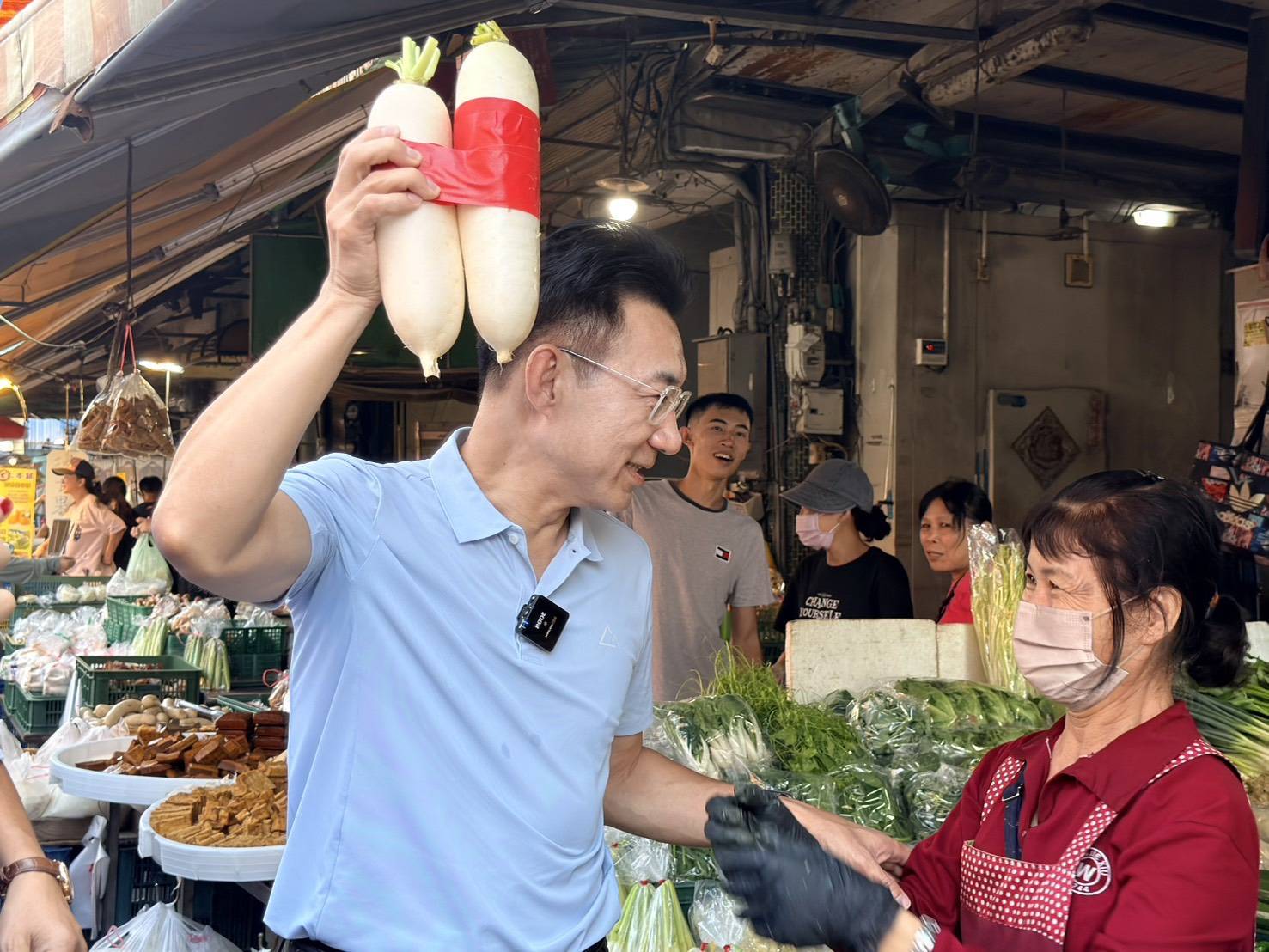 攤商送上象徵「好彩頭」的白蘿蔔，江啟臣舉起白蘿蔔逗趣合影