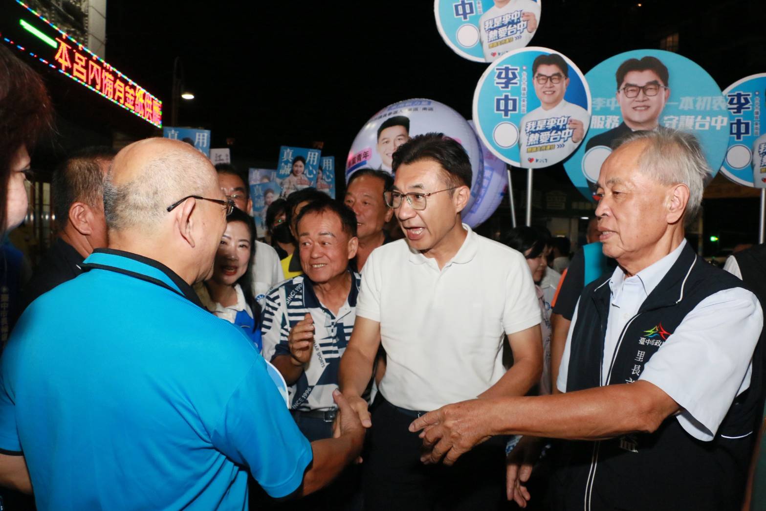 江啟臣在會場外與里長、鄉親握手寒暄，支持者高舉應援看板