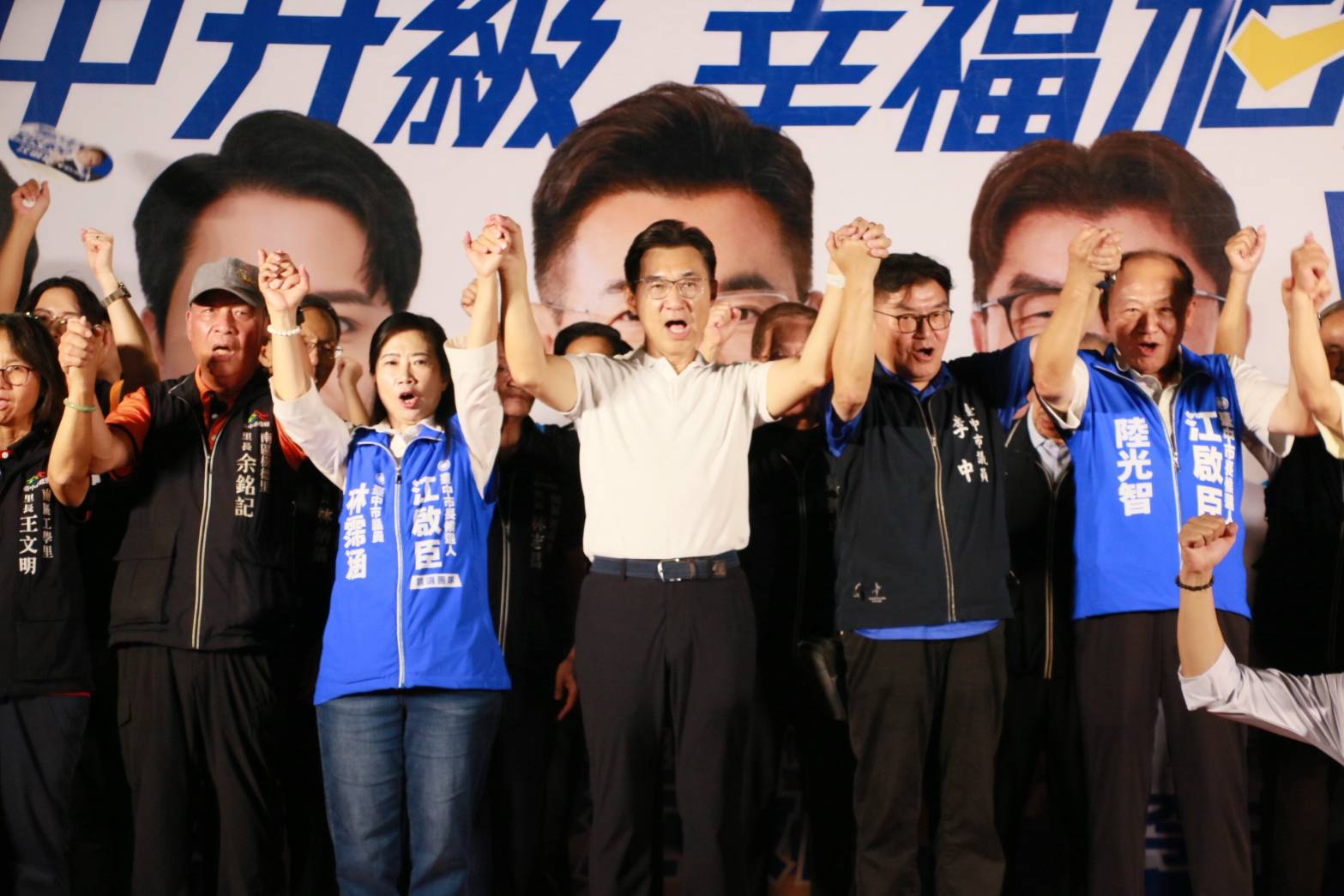 江啟臣與市議員李中、林霈涵及里長們在說明會舞台上牽手高舉，齊聲高喊口號