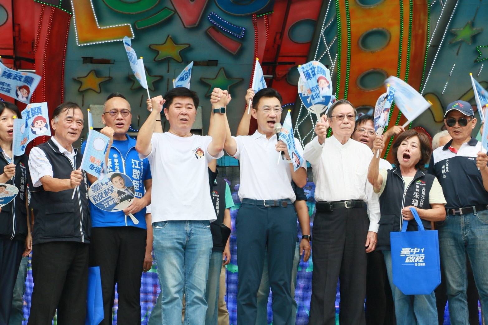 北區成立大會舞台上，江啟臣持麥克風與市議員陳政顯牽手高舉，支持者揮舞小旗