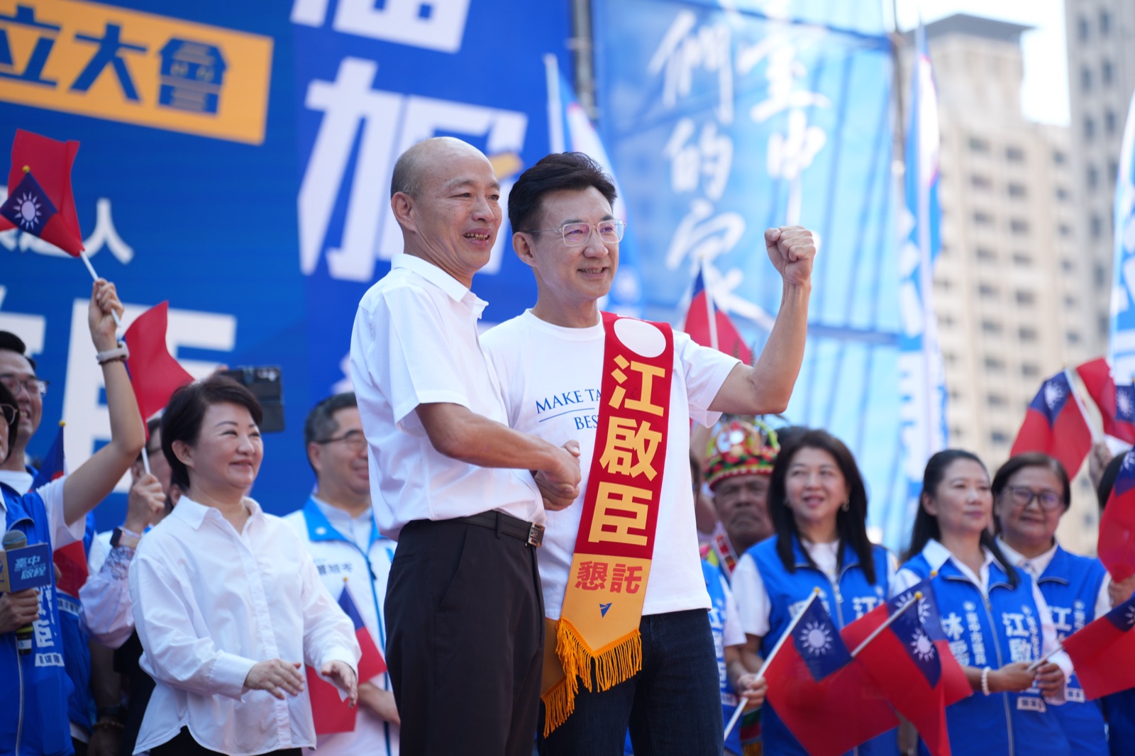江啟臣披著肩帶握拳，與身旁來賓握手致意