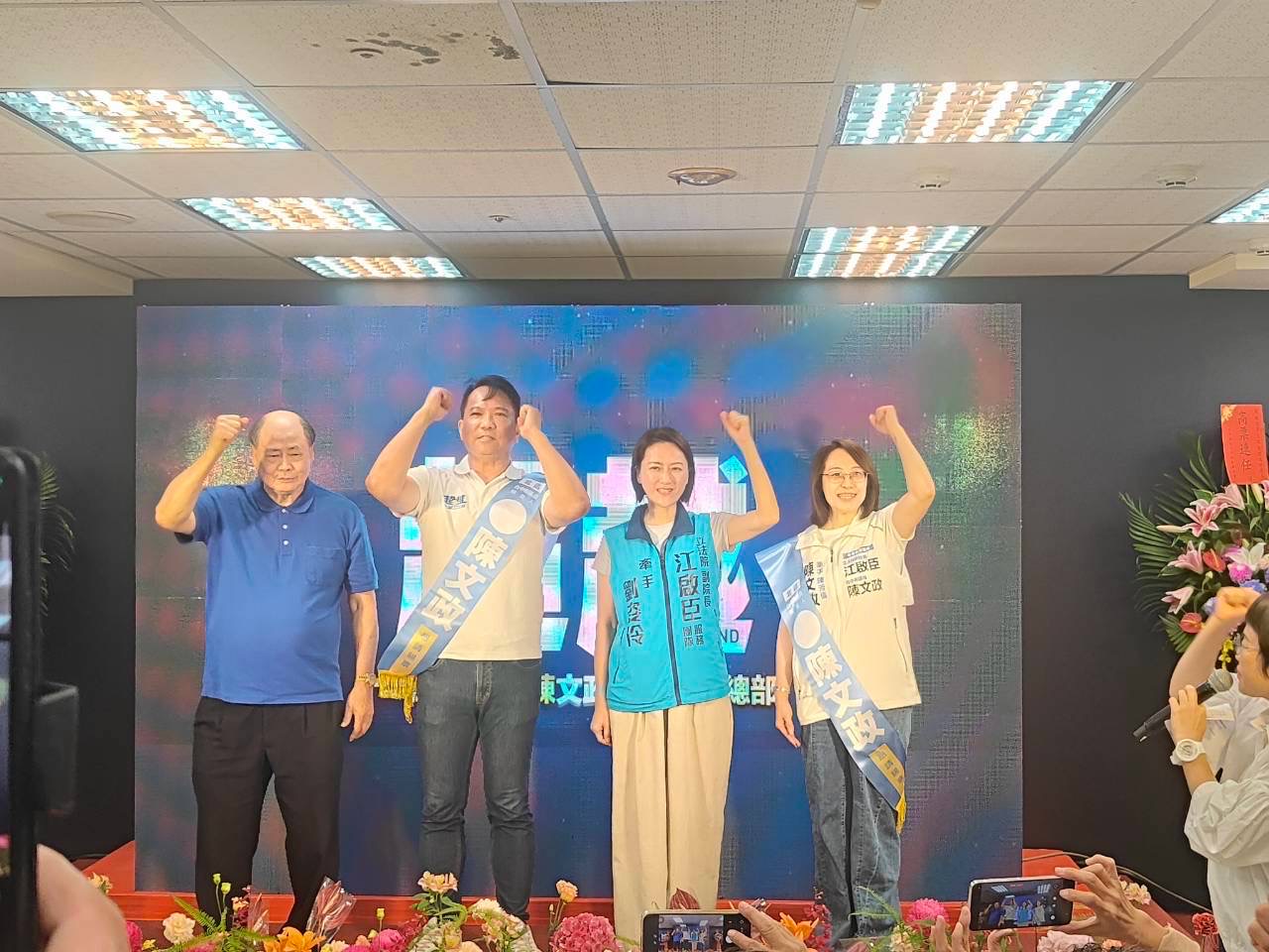 陳文政與身穿「江啟臣服務團隊」背心的劉姿伶等人在台上握拳合影