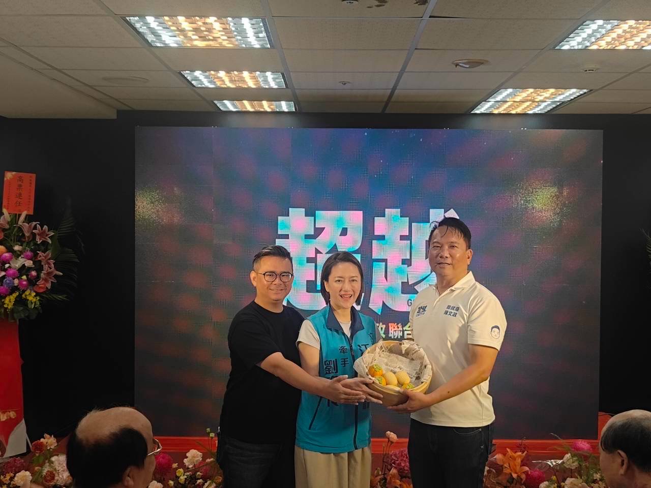 劉姿伶代表江啟臣出席，將一籃水果交給陳文政，另一位男士在旁牽手合影