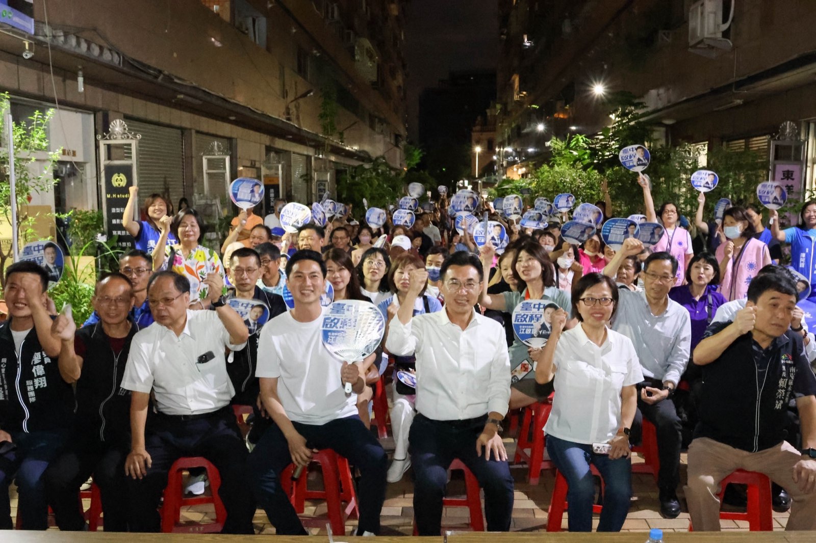 南屯問政說明會現場，江啟臣與廖偉翔、朱暖英及里長們坐在前排舉拳，後方支持者高舉應援扇