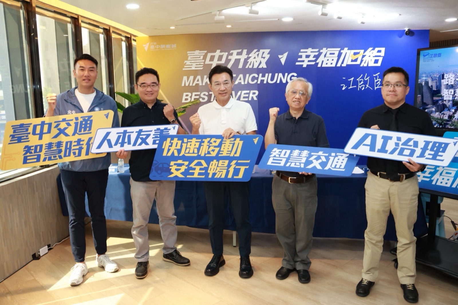 「臺中交通智慧時代」政策發佈記者會合影，五人手持「臺中交通 智慧時代」「人本友善」「快速移動 安全暢行」「智慧交通」「AI治理」等看板握拳，背後是「臺中升級 幸福加給」背板
