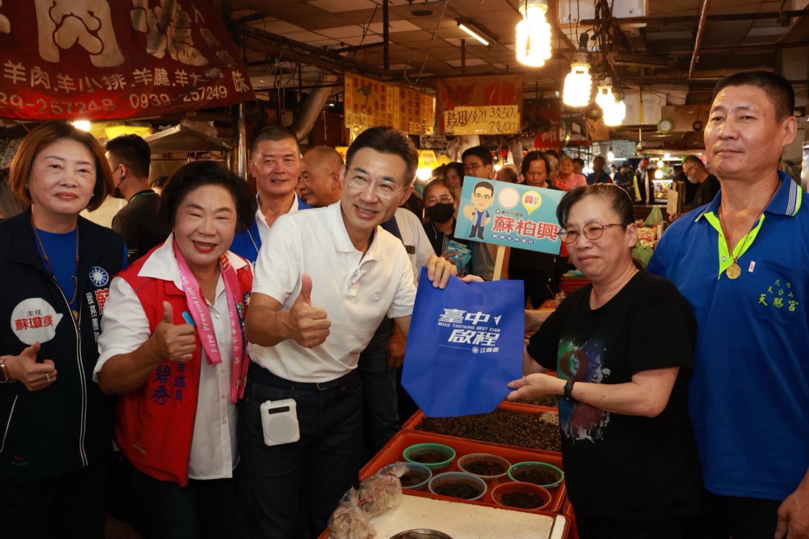 江啟臣與林碧秀在黃昏市場攤位前，向攤商遞上競選提袋並比讚