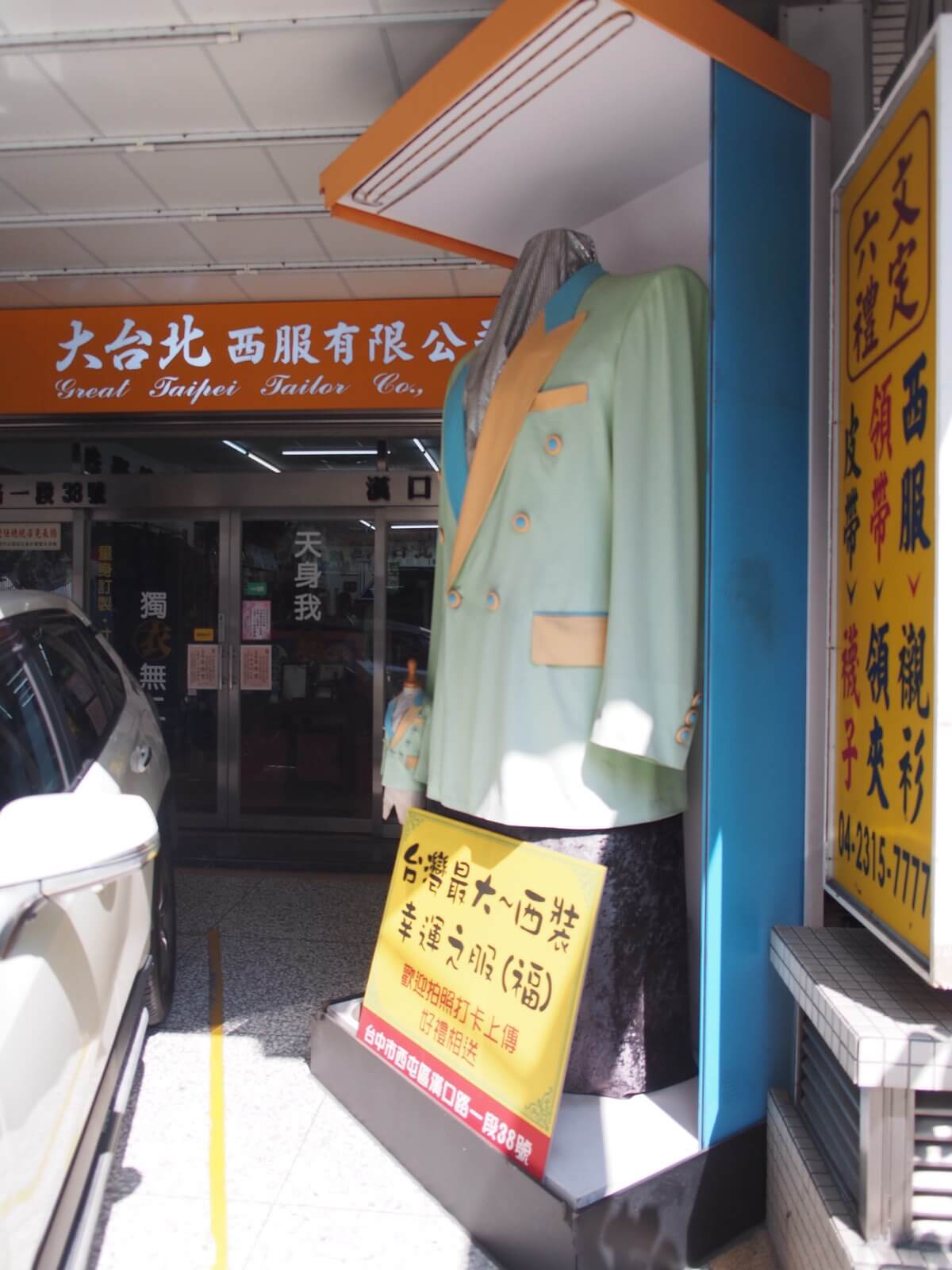 大台北西服有限公司西屯店門口的招牌，門邊立著一件立體展示的西裝外套
