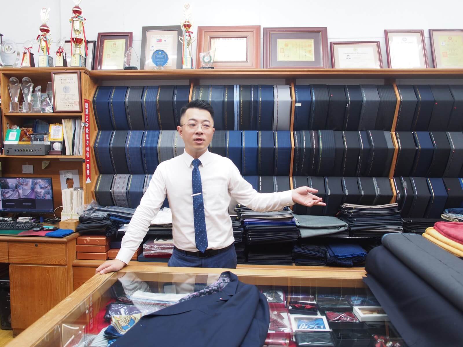利士杰在店內介紹攤放在展示櫃上的深藍色訂製西裝
