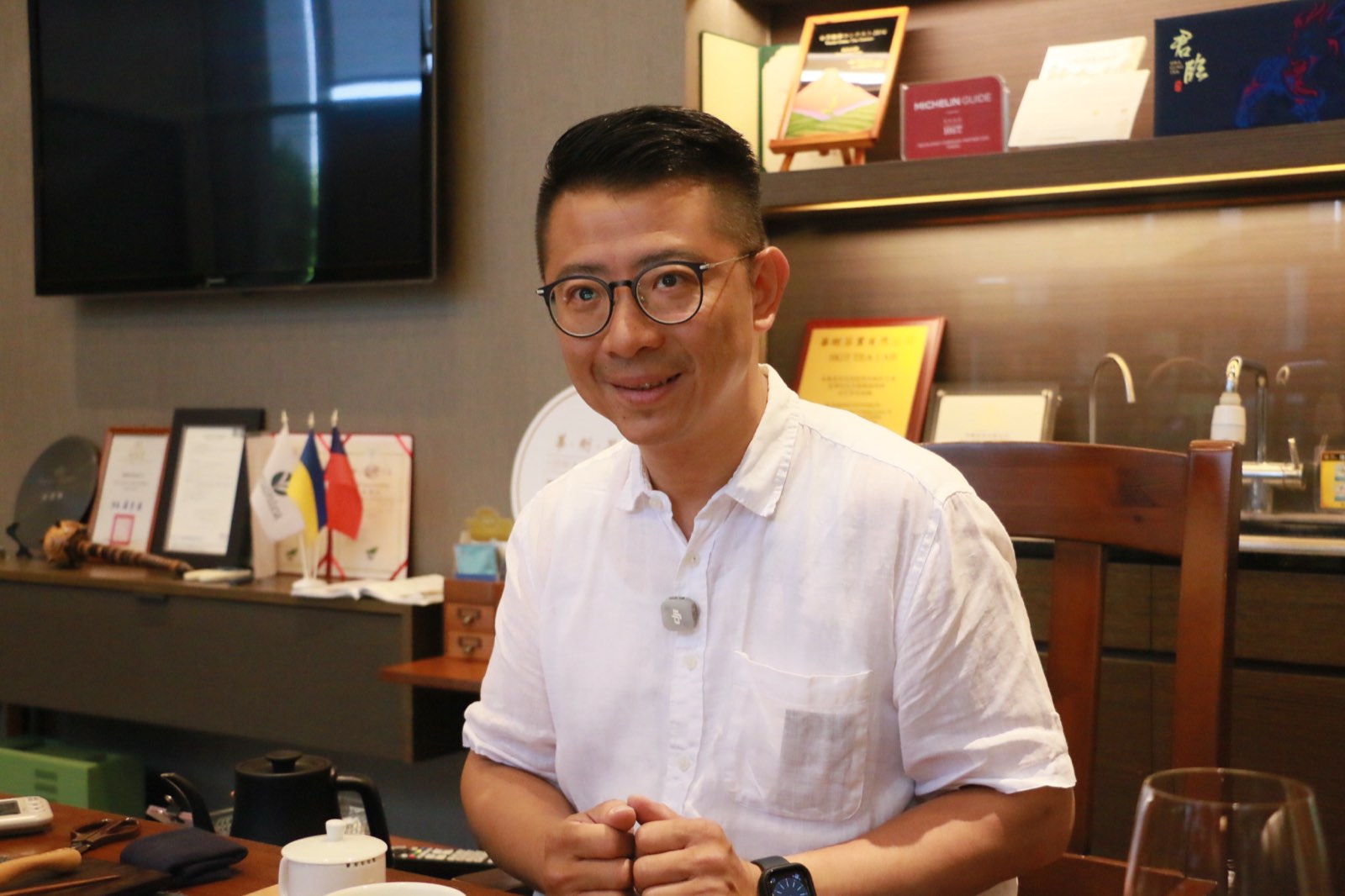 華剛茶業執行長杜蒼林站在門市內，雙手交握微笑