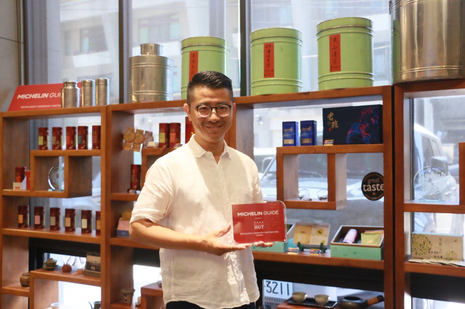 杜蒼林手持《米其林指南》的牌子，站在門市展示架前