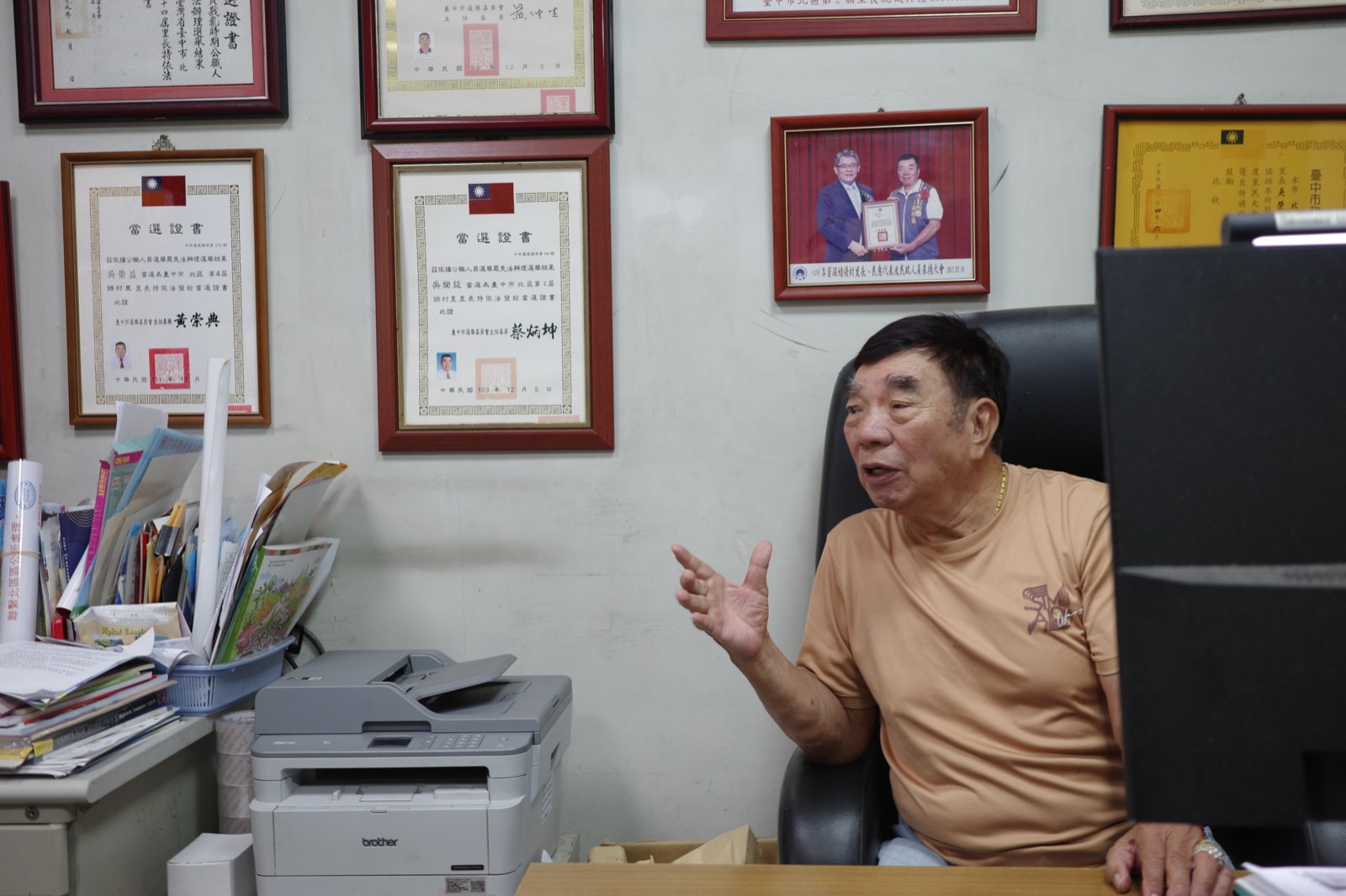 吳榮益坐在辦公室裡比著手勢說明